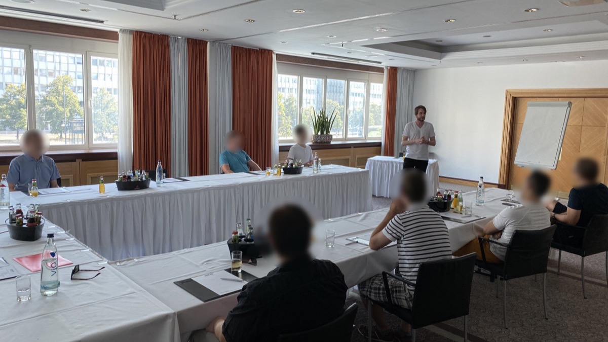 Seminar von Andreas Lorenz in Berlin: Teilnehmer an Tischen, der Coach steht vor dem Flipchart