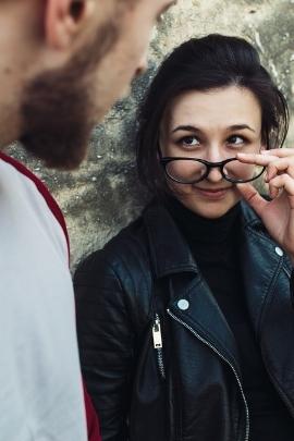 Frau zieht Brille von ihrer Nase und schaut Mann an