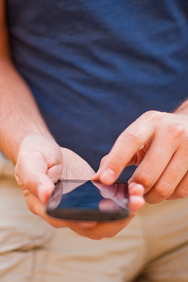 Mann hält Handy in der Hand und schreibt