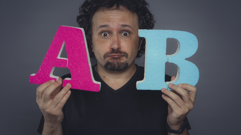 Mann mit fragendem Blick zeigt die Buchstaben A und B