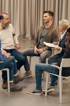 Männer sitzen im Stuhlkreis bei einer Selbsthilfegruppe