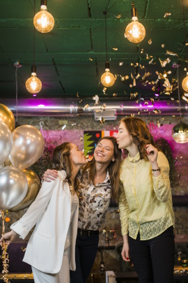 Drei Freundinnen stehen lachend in der Disco