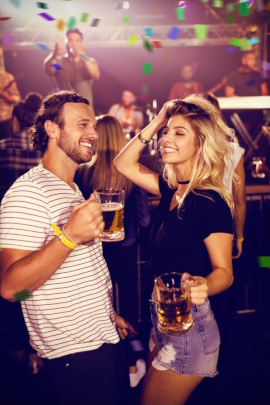 Mann und Frau mit Biergläsern flirten auf einer Party