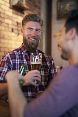 Zwei Männer im Club prosten sich mit Bier zu