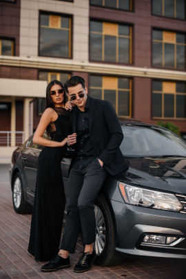 Elegantes Paar mit Sonnenbrille posiert vor dem Auto