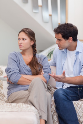 Paar sitzt beim Streit im Wohnzimmer auf dem Sofa