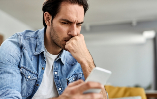 Mann schaut auf sein Handy und fragt sich, ob seine Ex-Freundin noch an ihm interessiert ist