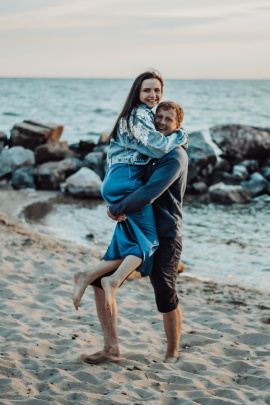 Mann und Frau toben lachend am Strand herum