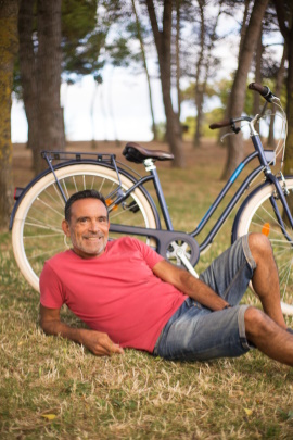 Glücklicher Mann liegt vor seinem Fahrrad auf der Wiese