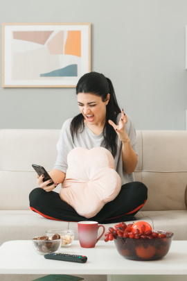 Frau auf Sofa schaut verärgert aufs Smartphone