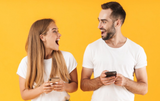 Paar mit Smartphones lacht sich fröhlich an
