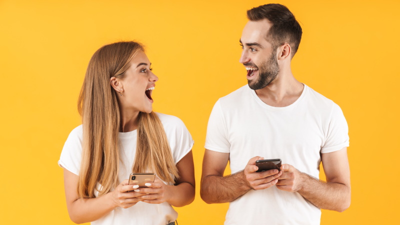 Paar mit Smartphones lacht sich fröhlich an