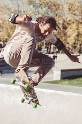 Mann mit Skateboard beim Sprung in der Halfpipe