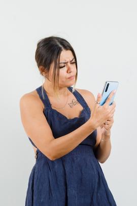 Frau schaut irritiert auf ihr Smartphone, weil ihr Chatpartner sich komisch verhält