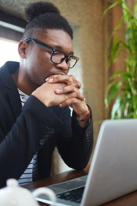 Mann schaut ratlos auf seinen Computer, weil er nicht weiß, ob er mit einem Catfish schreibt