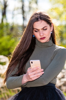 Frau schaut kritisch aufs Handy und sagt Date ab