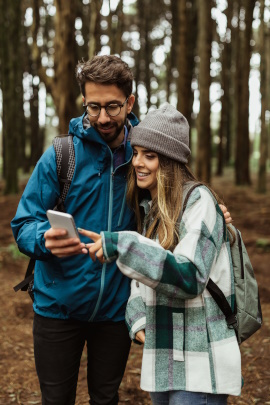 Paar wandert mit Smartphone durch den Wald
