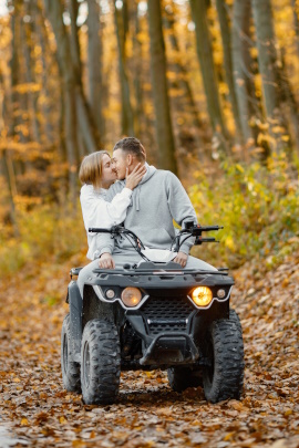 Mann und Frau küssen auf einem Quad im herbstlichen Wald