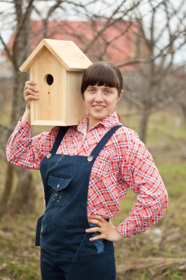 Frau trägt selbst gebautes Vogelhaus auf der Schulter