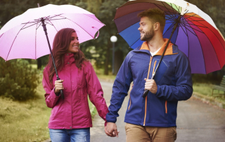 Mann und Frau beim Spaziergang mit Regenschirm