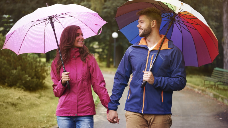 Mann und Frau beim Spaziergang mit Regenschirm