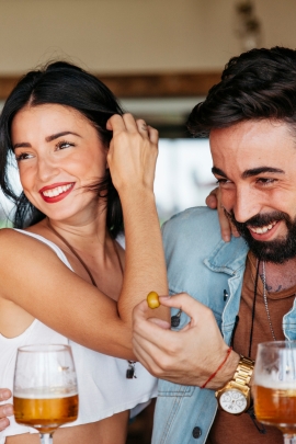 Mann und Frau trinken im Biergarten ein Bier und lachen herzlich