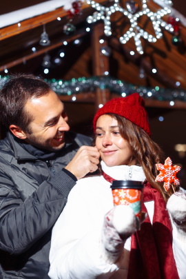 Paar mit Kaffeebecher flirtet auf dem Weihnachtsmarkt