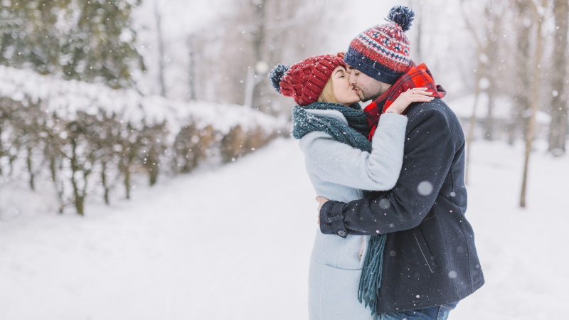 Paar beim Date im Winter küsst sich im Schnee