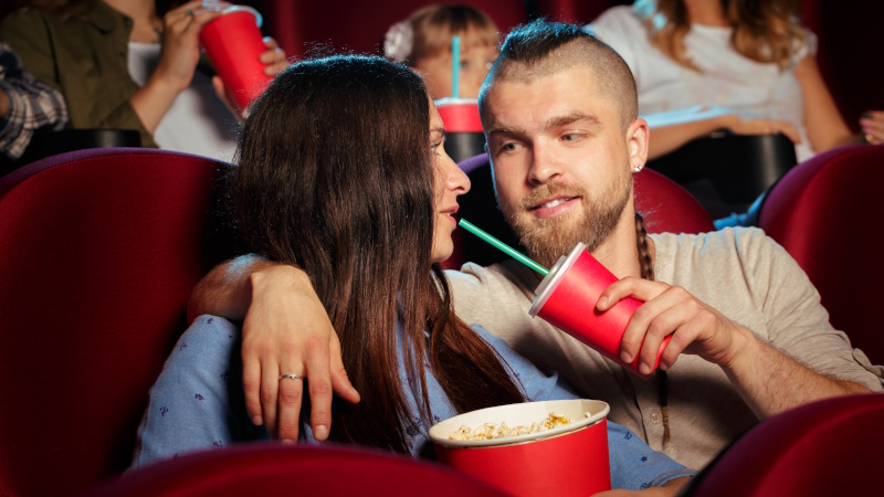 Verliebtes Paar sitzt im Kinosaal mit Popcorn und Cola
