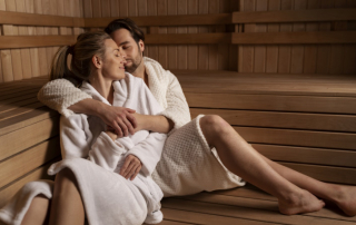 Mann und Frau in Bademänteln sitzen in der Sauna