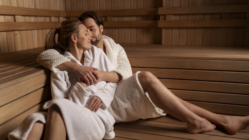 Mann und Frau in Bademänteln sitzen in der Sauna