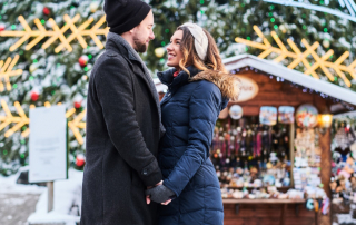 Glückliches Paar hält Händchen auf dem Weihnachtsmarkt
