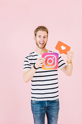 Mann hält lachend Instagram-Icon in die Kamera