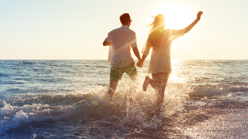 Glückliches Paar läuft durch das Wasser am Strand