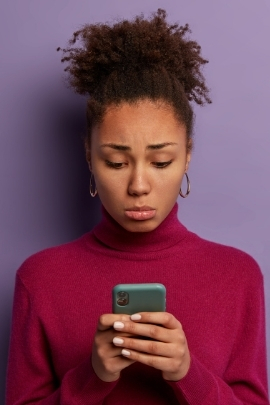 Frau schaut traurig auf das Smartphone, weil er nicht schreibt