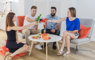 Zwei Paare sitzen zu Hause am Tisch und stoßen fröhlich an