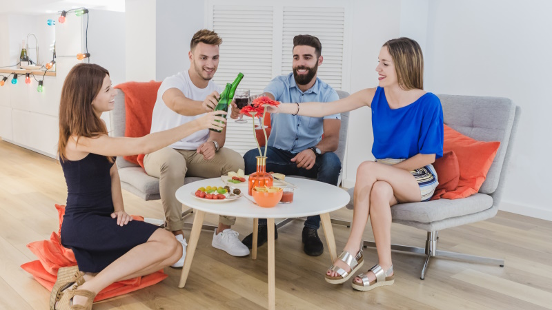 Zwei Paare sitzen zu Hause am Tisch und stoßen fröhlich an