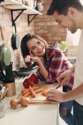 Mann und Frau lachend in der Küche beim Kochen