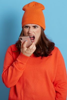 Frau mit Handy wütend über dumme Anmachsprüche auf Tinder