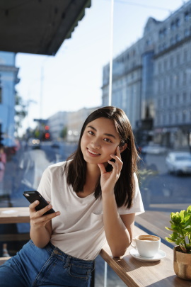 Lächelnde Frau mit Smartphone im Café