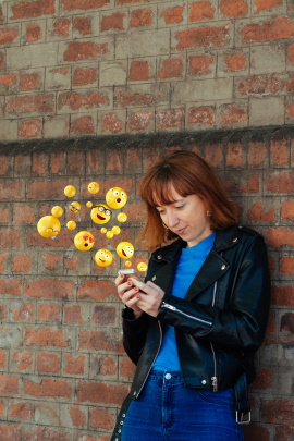 Frau beim Flirten am Handy bekommt viele Smileys geschickt