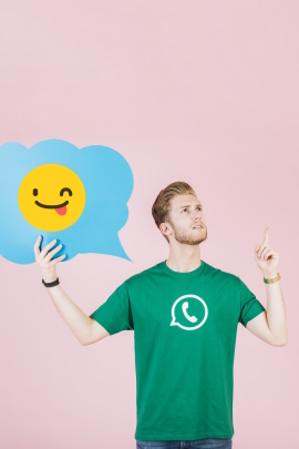 Mann im WhatsApp-Shirt hält Sprechblase mit Zwinker-Smiley