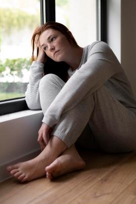 Frau schaut traurig aus dem Fenster, weil Mann sie verlassen hat