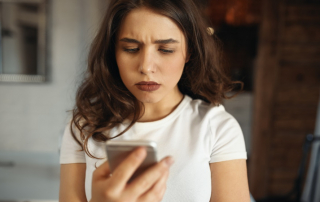 Frau schaut enttäuscht auf ihr Smartphone