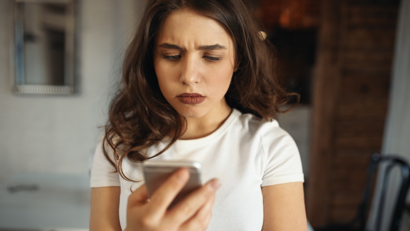 Frau schaut enttäuscht auf ihr Smartphone