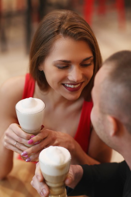 Paar mit Kaffee in den Händen lächelt sich verliebt an