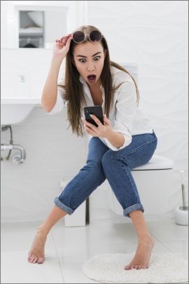 Frau sitzt auf dem Klo und blickt schockiert aufs Handy