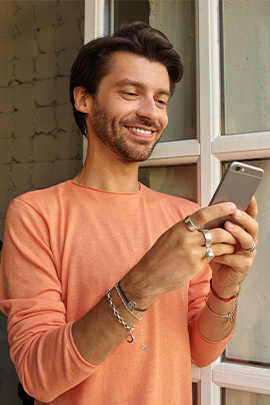 Mann schaut wegen Nachricht von Ex lächelnd aufs Handy