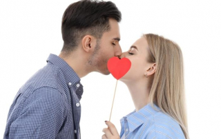 Mann und Frau küssen sich hinter Papier-Herz