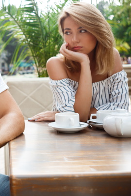 Frau sitzt gelangweilt am Tisch beim Date im Café